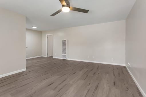 A room with a ceiling fan and wooden flooring.