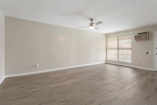 A room with a ceiling fan and a window with blinds.