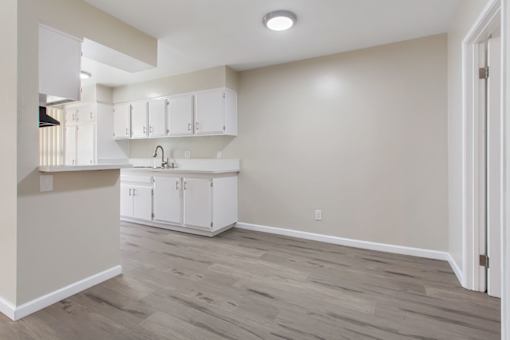 A kitchen with white cabinets and a wooden floor.