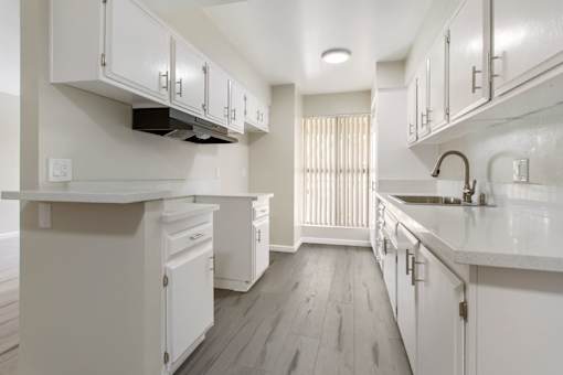 A white kitchen with wood floors and white cabinets.