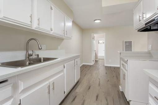 A kitchen with white cabinets and a wooden floor.