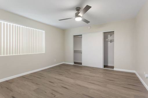 A room with a ceiling fan and wooden flooring.