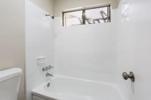A white bathroom with a tub and a window.
