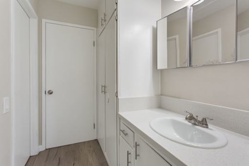 A white bathroom with a sink and mirror.