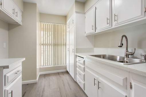 A kitchen with white cabinets and a sink.