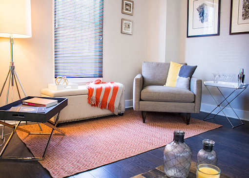 A living room with a grey couch, a coffee table, and a lamp.