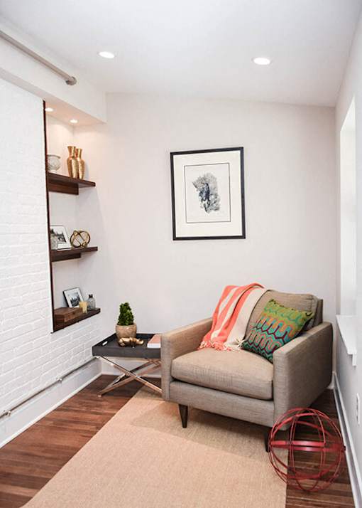 A living room with a grey couch, a small table, and a framed picture on the wall.