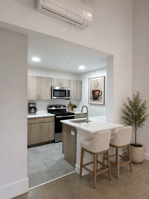 A kitchen with a white countertop and wooden bar stools.