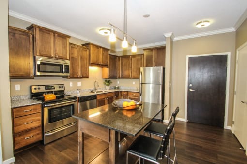 a kitchen with wooden cabinets and stainless steel appliances at The Flats at Cedar Grove, Minnesota, 55122
