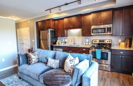 a living room with a blue couch in front of a kitchen  at Victoria Park and V2 Apartments, St. Paul, MN