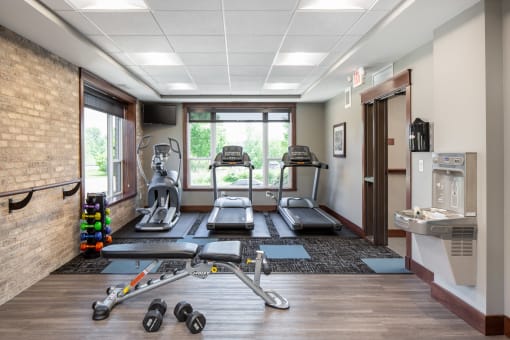 the fitness room filled with exercise equipment  at Victoria Park and V2 Apartments, Minnesota