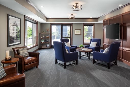 a community room filled with furniture and a large window  at Victoria Park and V2 Apartments, St. Paul, 55102