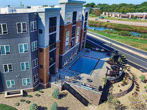 an aerial view of a building with a pool in front of it at The Flats at Cedar Grove, Eagan