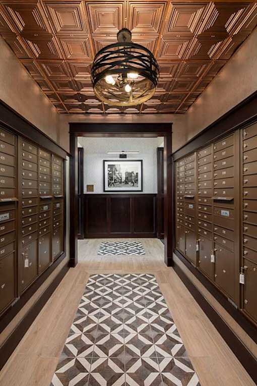 A hallway with a patterned carpet and a chandelier hanging from the ceiling.
