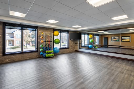 a fitness room with a large screen tv and colorful yoga balls on the wall at The Gallery Apartments, Burnsville