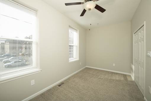 an empty bedroom with a ceiling fan and two windows at Queen Anne Belvedere, Baltimore, MD