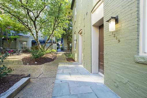 a walkway between two buildings with trees and plants at Queen Anne Belvedere, Baltimore, 21201