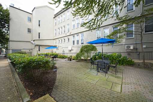 a patio with tables and umbrellas in a courtyard at Queen Anne Belvedere, Baltimore, MD