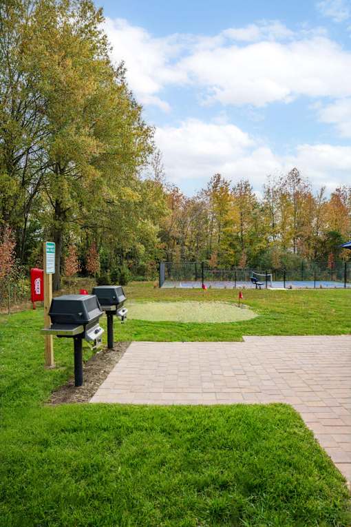 A park with a bench and a trash can at The Promenade at Easton Apartments, Easton Maryland