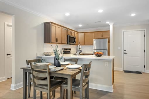 A kitchen with a table set for two with a bowl of fruit on the counter at The Promenade at Easton Apartments, Easton, MD 21601