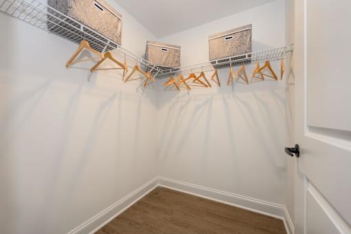 A hallway with a white wall and a wooden floor with a metal rack on the wall at The Promenade at Easton Apartments, Maryland, 21601