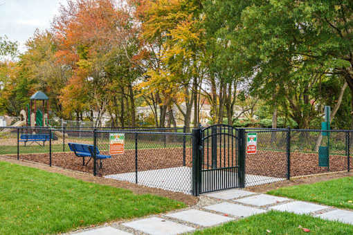 A playground with a black fence and a green slide at The Promenade at Easton Apartments, Easton, MD 21601