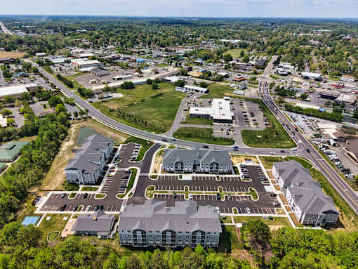 A bird's eye view of a large building complex surrounded by a parking lot and a road.