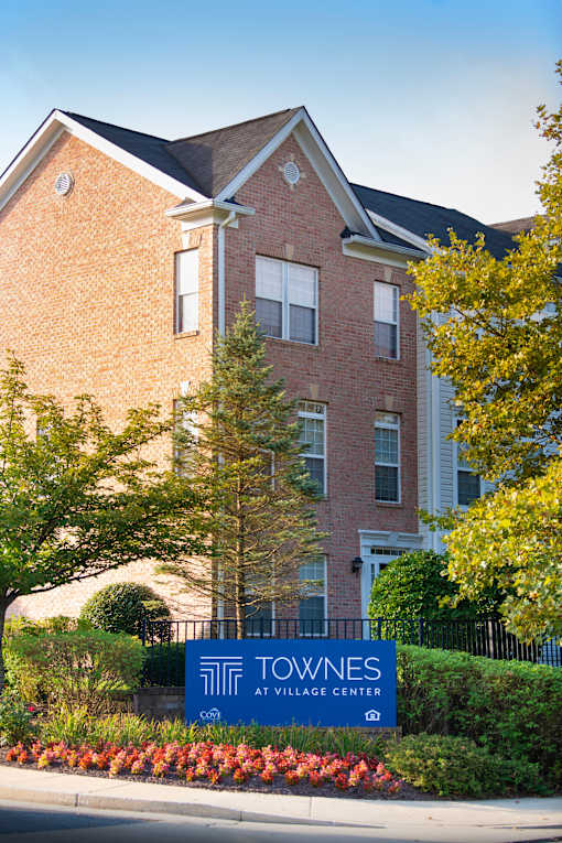a building with a blue sign in front of it at Townes at Village Center Apartments, Reisterstown, Maryland