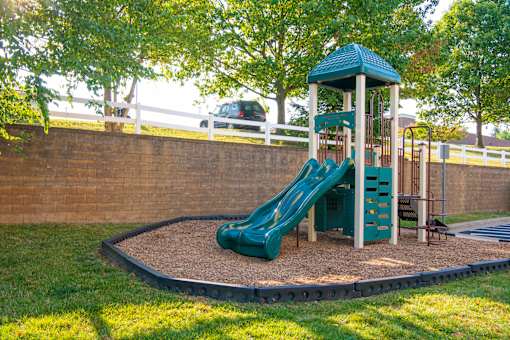 a playground with a slide in a park at Townes at Village Center Apartments, Reisterstown, 21136