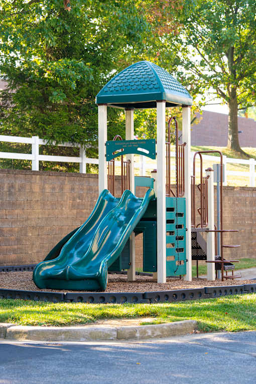 a playground with a slide and a swing set at Townes at Village Center Apartments, Reisterstown, MD