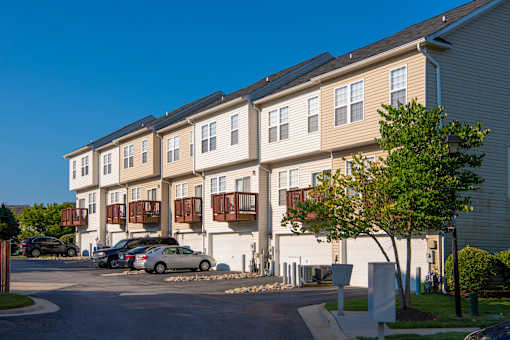 an apartment building with cars parked in front of it at Townes at Village Center Apartments, Reisterstown, 21136