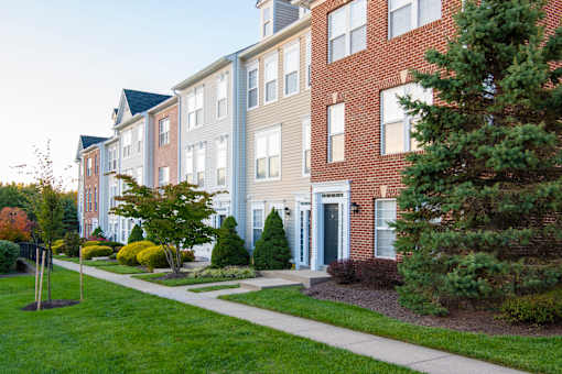 Building exterior with garden and trees at Townes at Village Center Apartments, Maryland, 21136