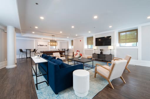 A living room with a blue couch and a white ottoman.