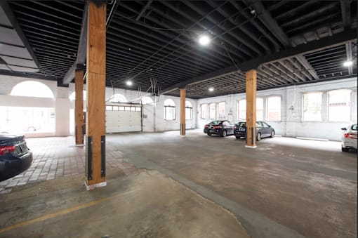 A parking garage with a few cars and wooden pillars.