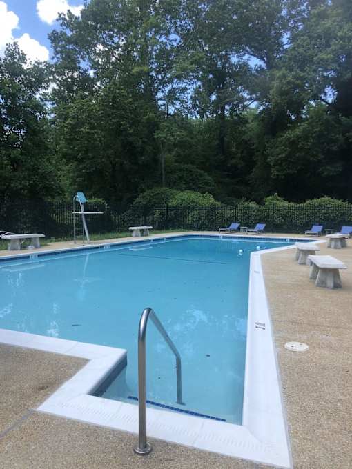 A swimming pool surrounded by trees and benches.