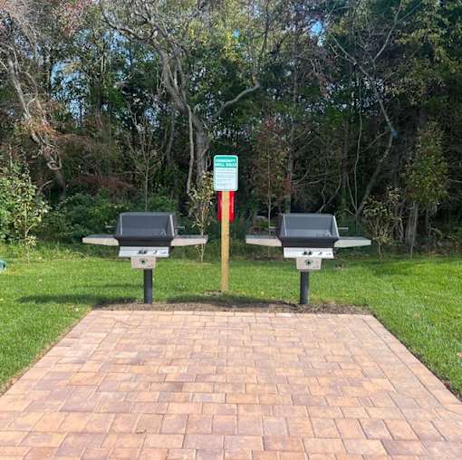 Two benches are placed on a brick pathway in a park at The Promenade at Easton Apartments, Maryland, 21601