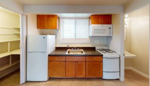 A kitchen with white appliances and wooden cabinets.