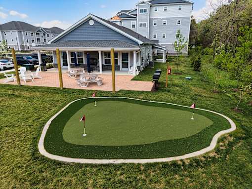 A small putting green is in front of a house.