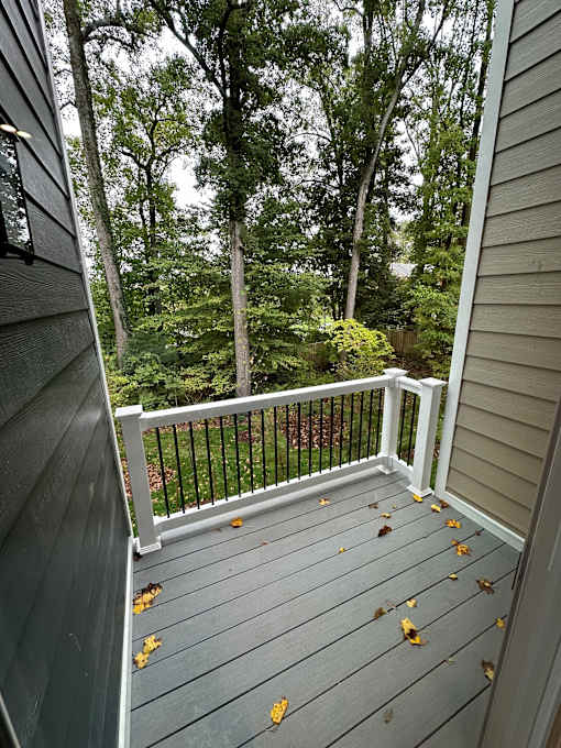 A balcony with a railing and leaves on the floor.