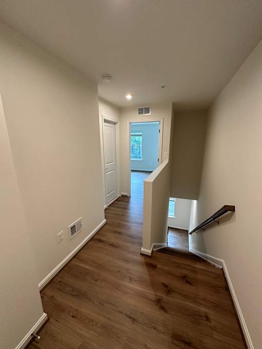 A hallway with wood floors and white walls.