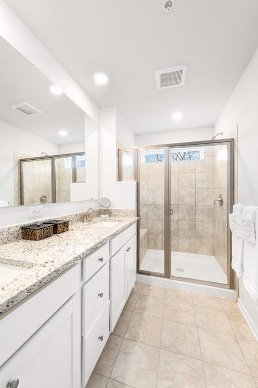 A bathroom with a walk-in shower and a vanity with a marble countertop.at Forge Overlook, Halethorpe, MD