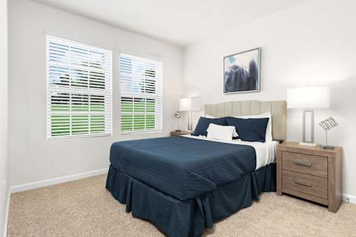 A bedroom with a bed, nightstand, and window with blinds. at Forge Overlook, Halethorpe