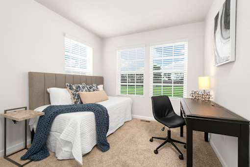 A bedroom with a bed, desk, and chair. at Forge Overlook, Halethorpe