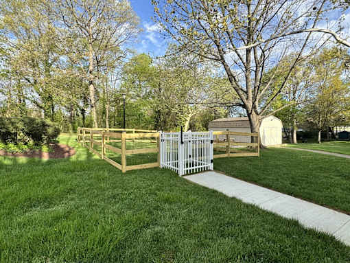 A white fence with a gate is in front of a grassy area. at West Woods, Annapolis, Maryland