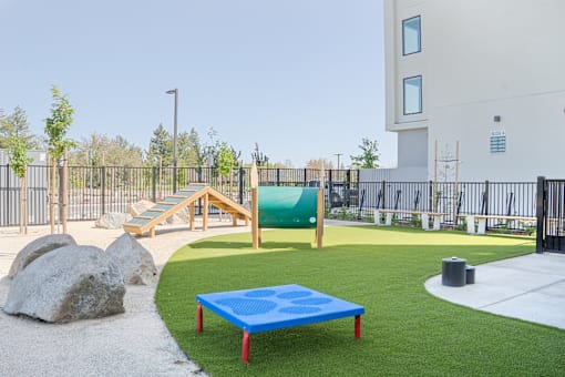 A playground with a blue mattress and a slide.