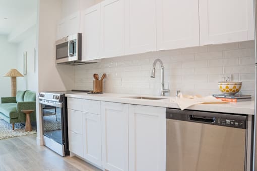 A kitchen with white cabinets and a black microwave above the oven.
