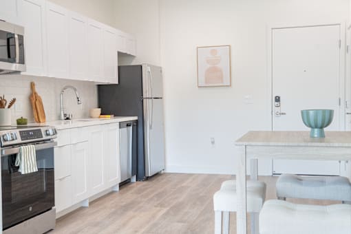 A kitchen with white cabinets and a black refrigerator.
