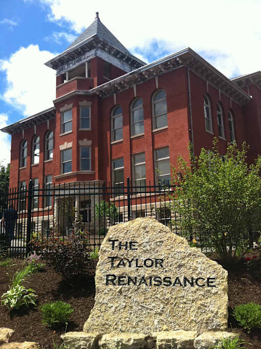A red brick building with a stone in front that says "The Taylor Renaissance".