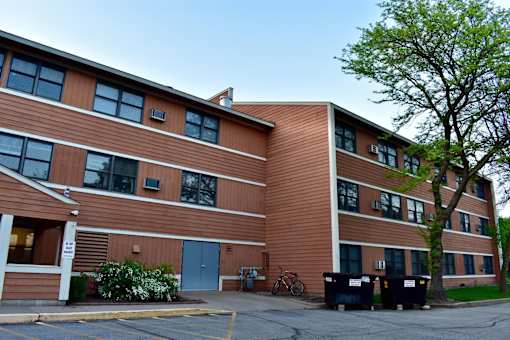 A building with a brown facade and a tree in front.