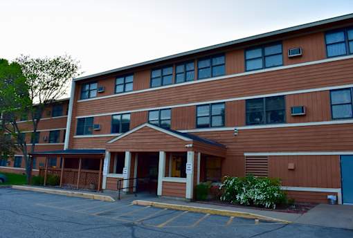 A brown building with a parking lot in front.